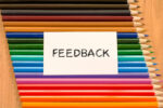 close up of coloured pencils with a paper sign saying "feedback"