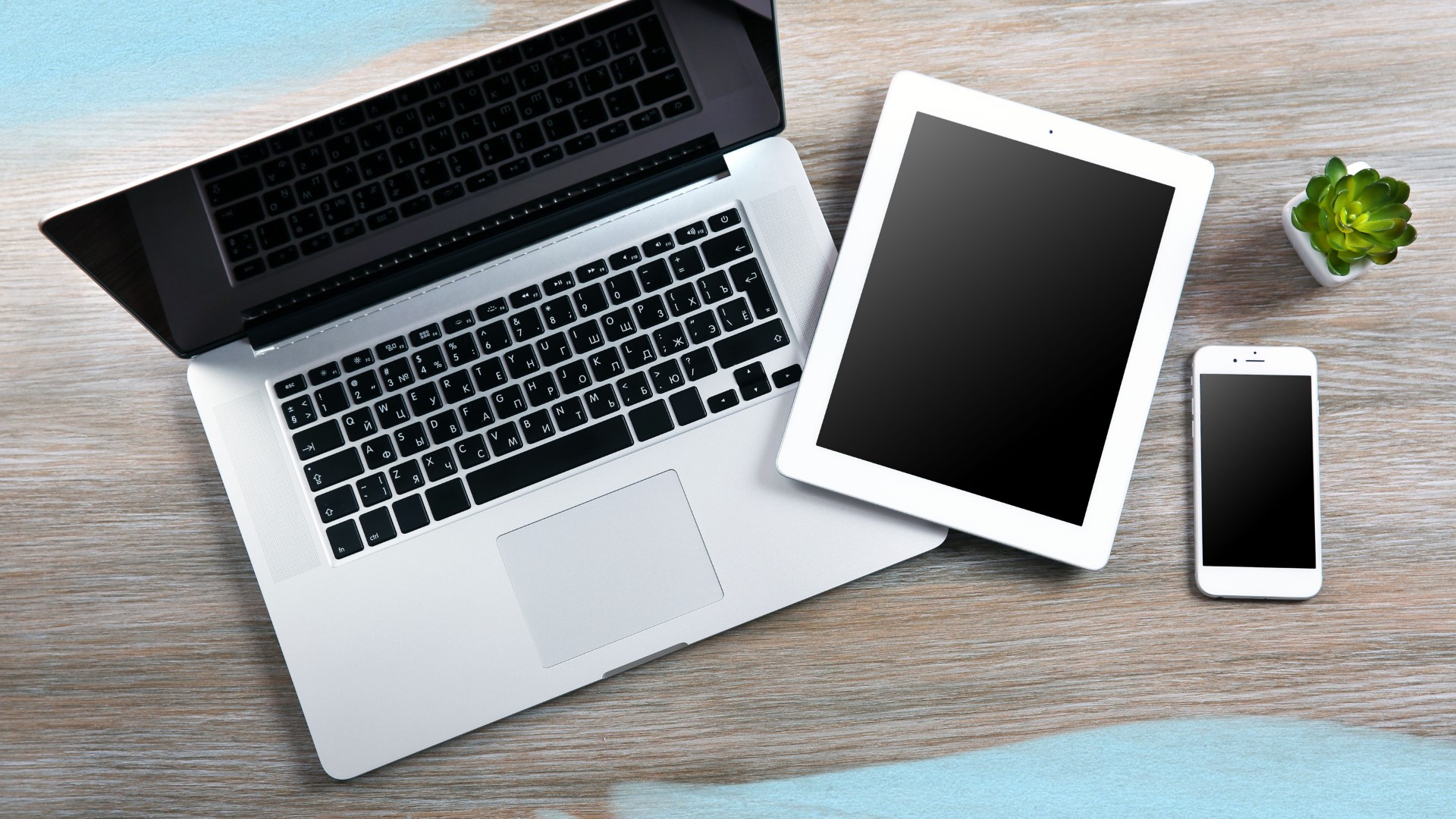 open laptop with an ereader and smartphone on a desk.