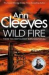 Book cover of Wild Fire by Ann Cleeves shows a red sky and a wooden fence