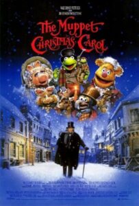 The Muppet Christmas Carol movie promo cover shows Miss Piggy, Kermit and Fozzie as well as a Michael Cain as Mr. Scrooge. Scrooge walks down a snowy town street with his cane.